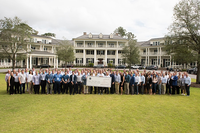 large group of financial advisors outside holding giant check