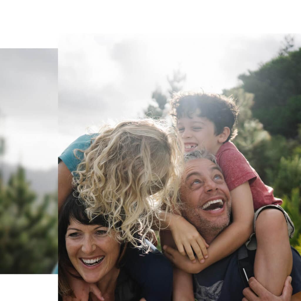 happy family with kids riding parents shoulders